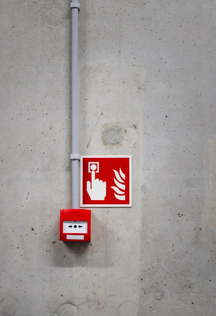 pexels photo 30535093 A red fire alarm switch with a warning sign on a concrete wall, highlighting safety in industrial settings.