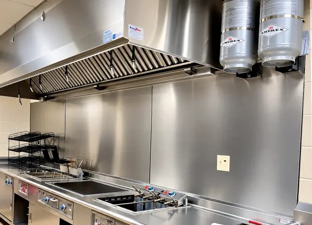 Cocina industrial de acero inoxidable con campanas extractoras y equipos profesionales de cocción